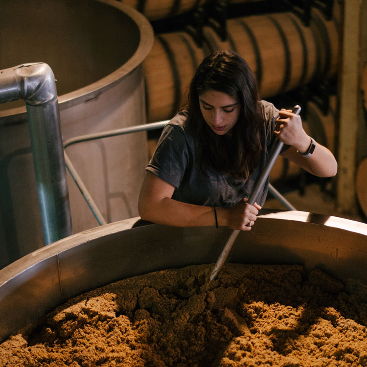 Women stirs batch of whiskey.